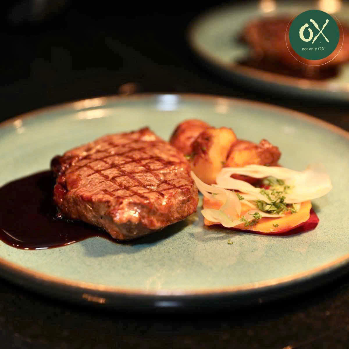 Grilled steak with vegetables and dark sauce on a grey plate