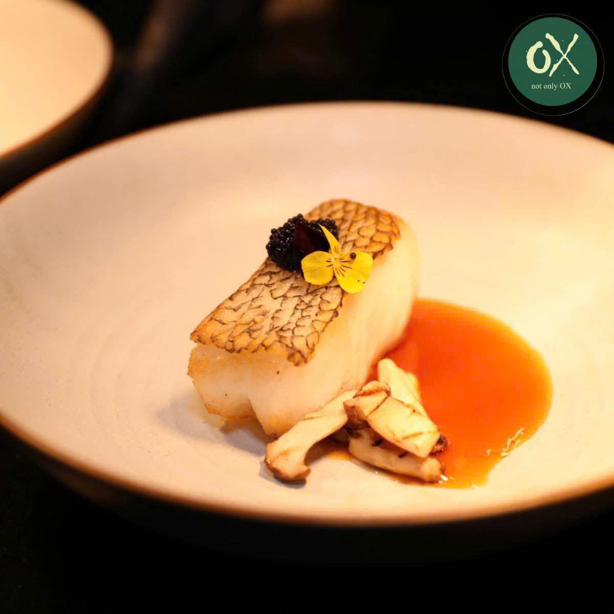 Pan-fried fish with mushrooms and orange sauce on a white plate