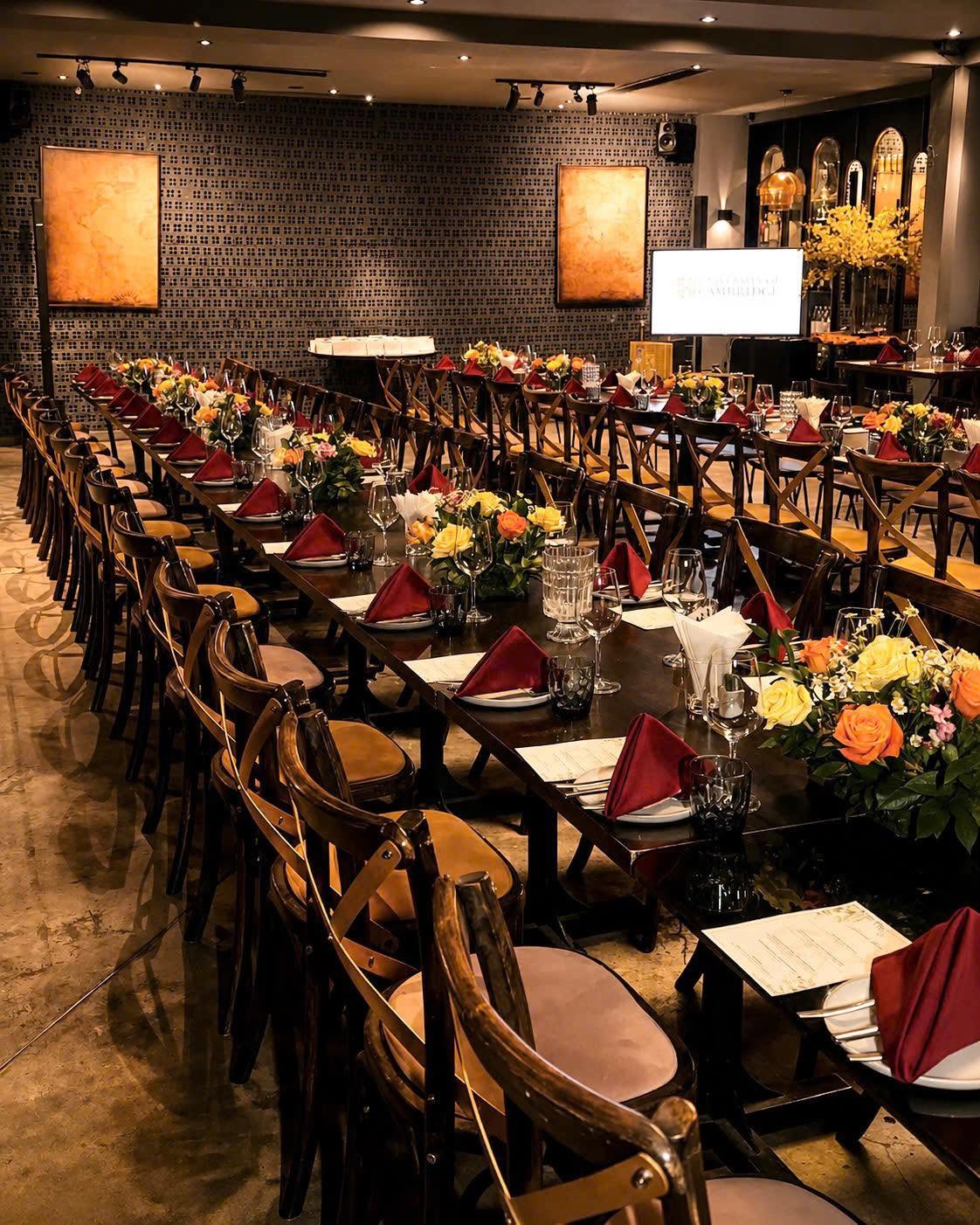 The OX arranged with long banquet tables, yellow roses and burgundy napkins
